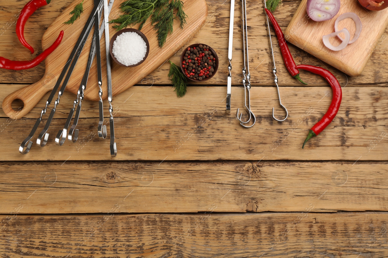 Photo of Flat lay composition with metal skewers on wooden table. Space for text