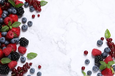 Photo of Many different fresh ripe berries on white marble table, flat lay. Space for text