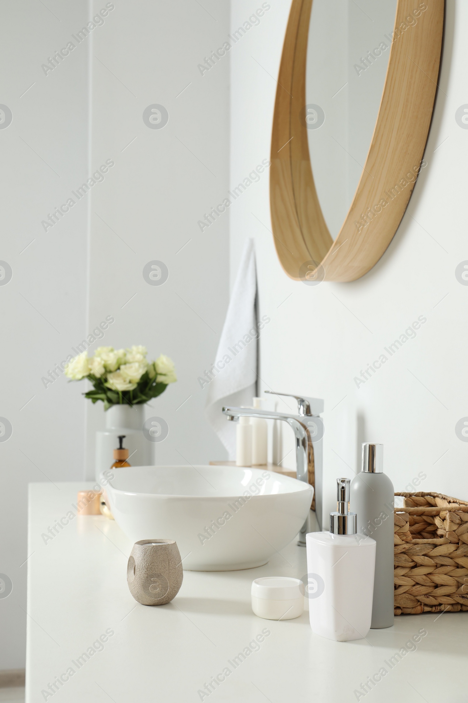 Photo of Vase with beautiful white roses and toiletries near sink in bathroom