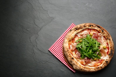 Tasty pizza with meat and arugula on black table, top view. Space for text