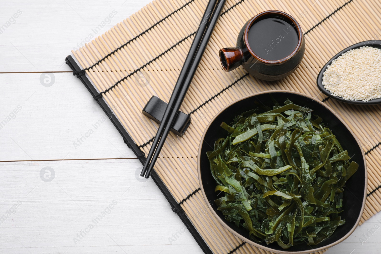 Photo of Fresh laminaria (kelp) seaweed served on white wooden table, flat lay