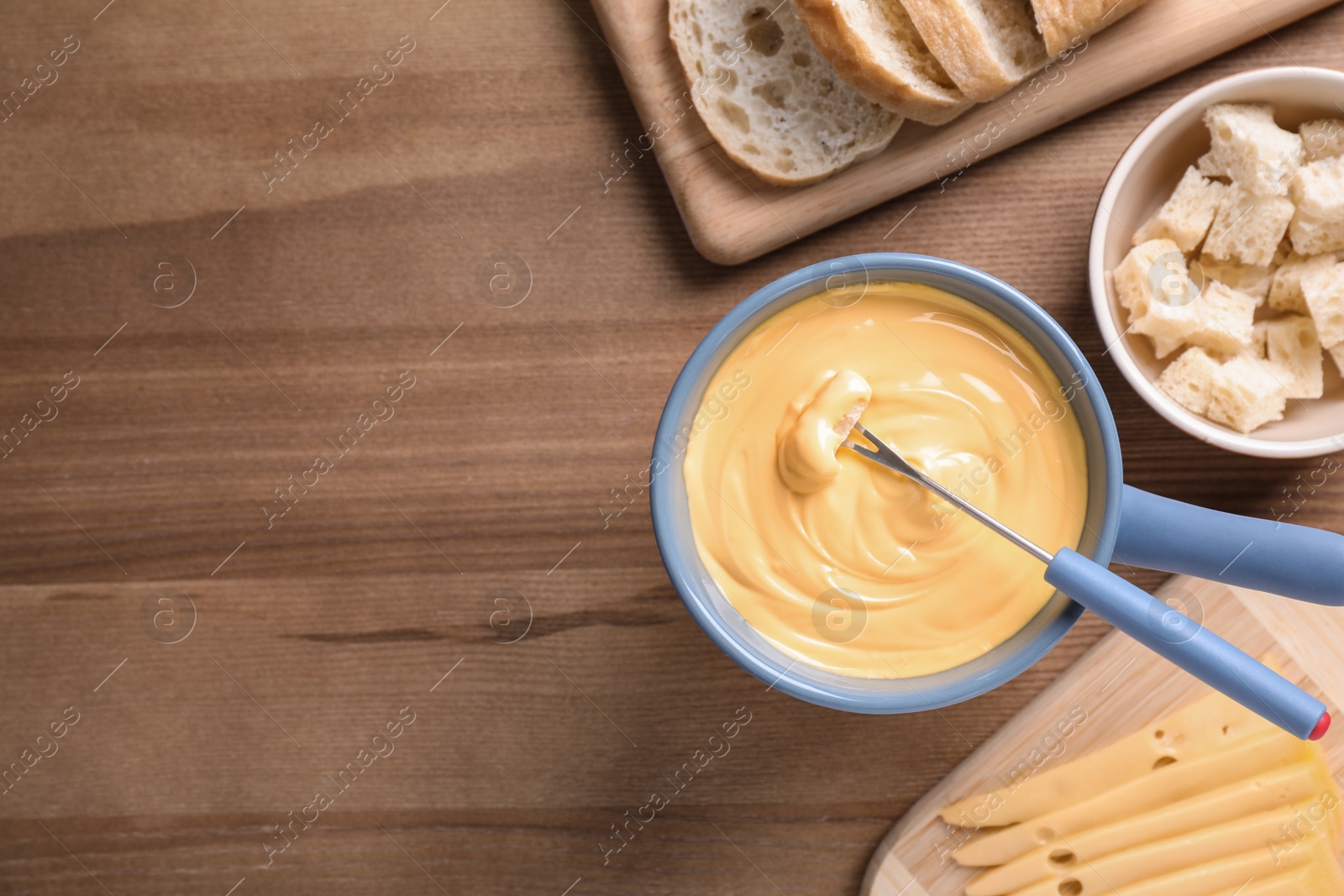 Photo of Flat lay composition with cheese fondue and bread on wooden table, space for text