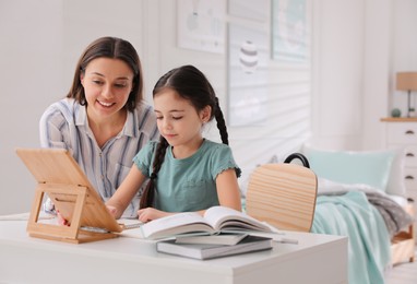 Mother helping her daughter doing homework with tablet at home