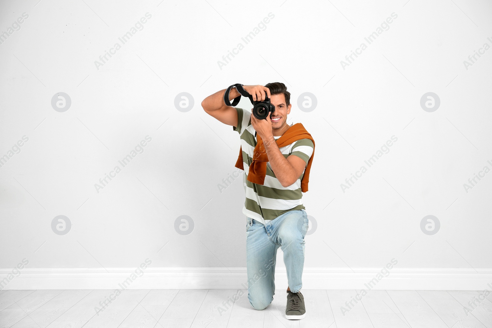 Photo of Professional photographer working near white wall in studio