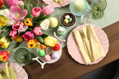 Festive Easter table setting with beautiful flowers and painted eggs, top view