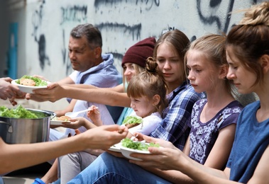 Poor people receiving food from volunteer outdoors