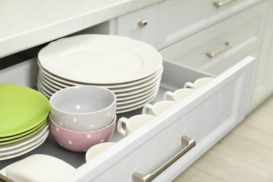 Photo of Clean plates, bowls and cups in drawer indoors