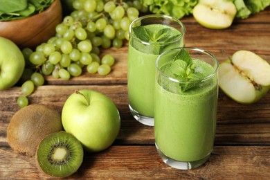 Photo of Green smoothie in glasses and fresh ingredients on wooden table