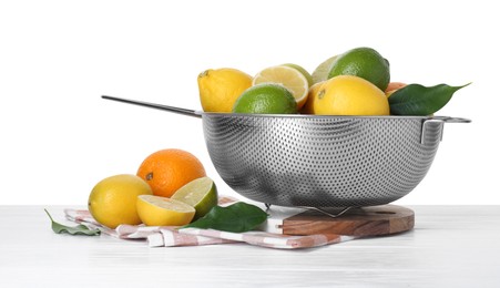 Photo of Metal colander with citrus fruits on table against white background