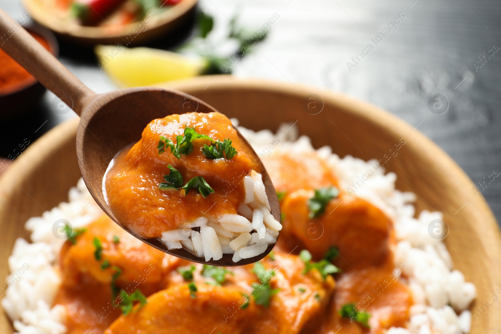 Photo of Spoon with tasty butter chicken over bowl of meal, closeup