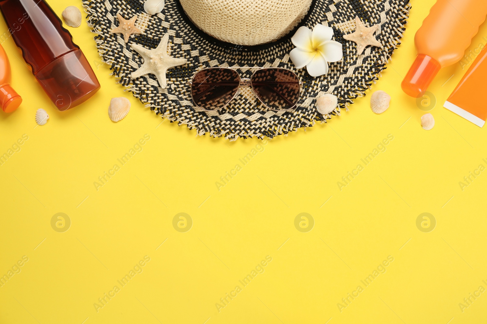 Photo of Sun protection products and beach accessories on yellow background, flat lay. Space for text