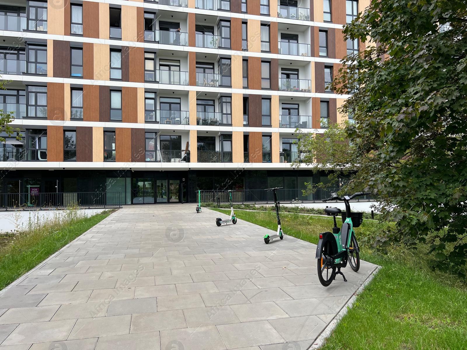 Photo of Electronic scooters and bicycle parked near building on city street