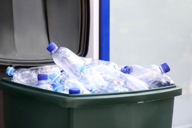 Many used plastic bottles in trash bin outdoors, closeup. Recycling problem