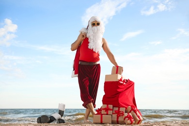 Santa Claus with bag of presents on beach. Christmas vacation
