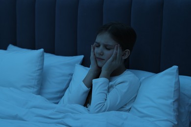 Little girl suffering from headache in bed at night