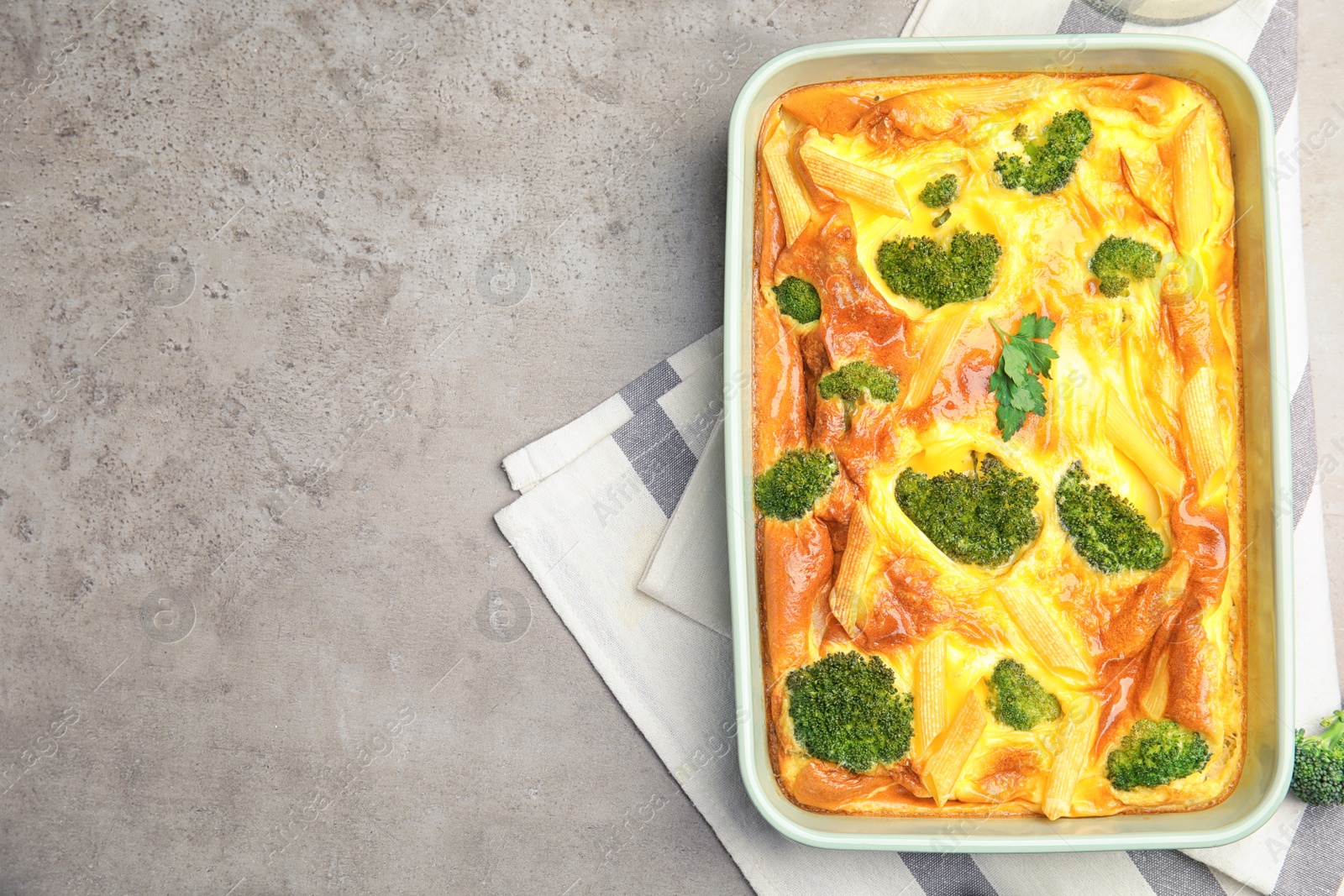 Photo of Tasty broccoli casserole in baking dish on grey table, top view. Space for text