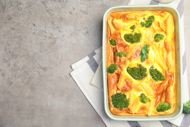 Tasty broccoli casserole in baking dish on grey table, top view. Space for text