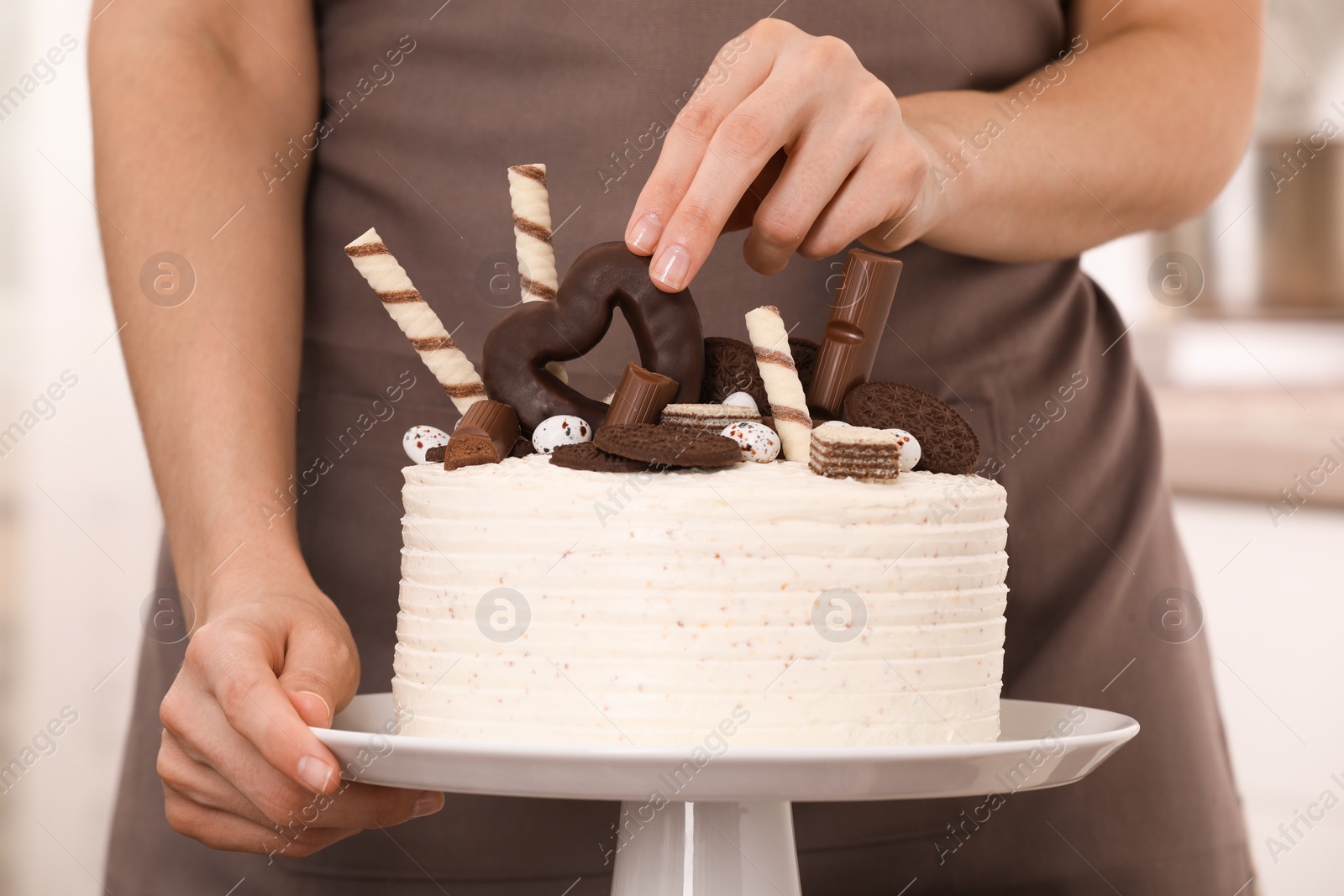 Photo of Woman decorating delicious cake with sweets, closeup