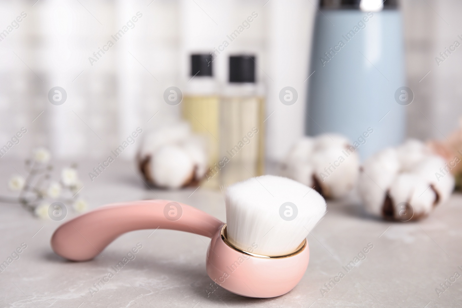 Photo of Modern face cleansing brush on light grey marble table. Cosmetic accessory