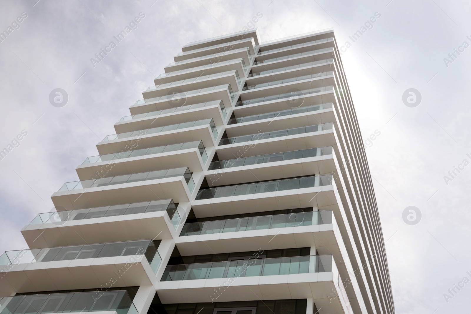 Photo of Exterior of residential building with balconies against blue sky, low angle view