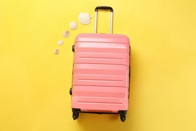 Photo of Stylish suitcase and seashells on color background, top view