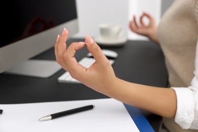 Photo of Businesswoman meditating at workplace, closeup. Zen concept