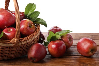 Photo of Ripe red apples and leaves on wooden table against white background