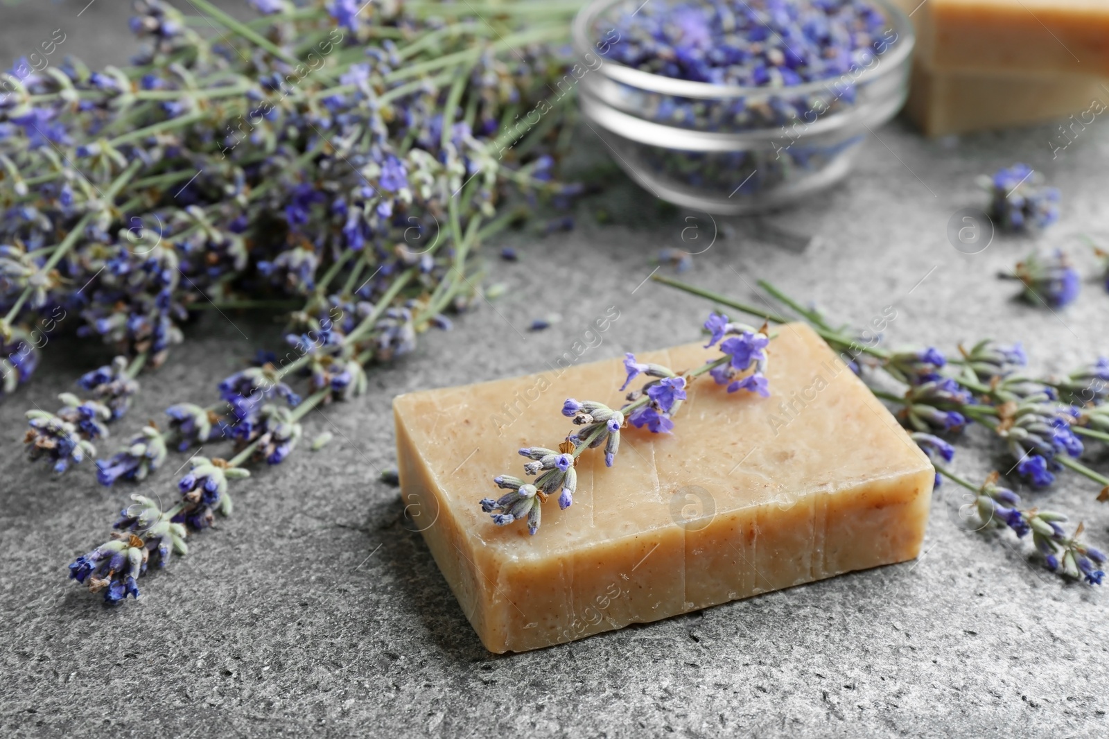 Photo of Hand made soap bar with lavender flowers on grey stone table