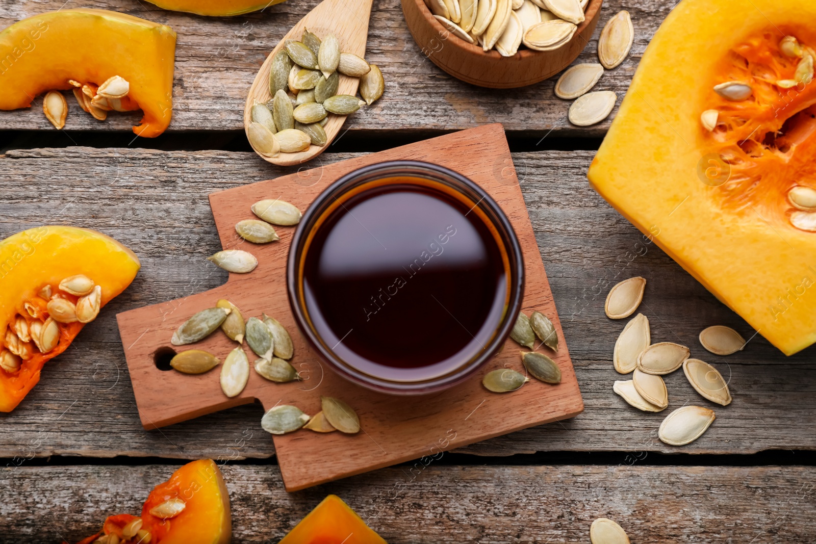 Photo of Flat lay composition with fresh pumpkin seed oil in glass bowl on wooden table