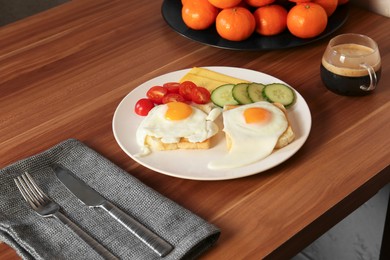 Tasty toasts with fried eggs, cheese and vegetables on wooden table
