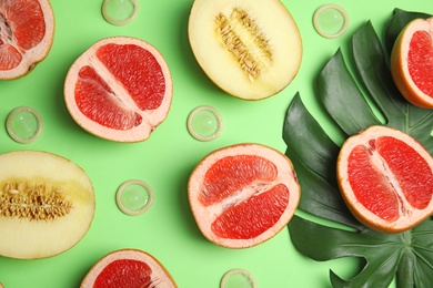 Photo of Flat lay composition with condoms and exotic fruits on green background. Erotic concept