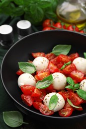 Photo of Tasty salad Caprese with tomatoes, mozzarella balls and basil on table, closeup