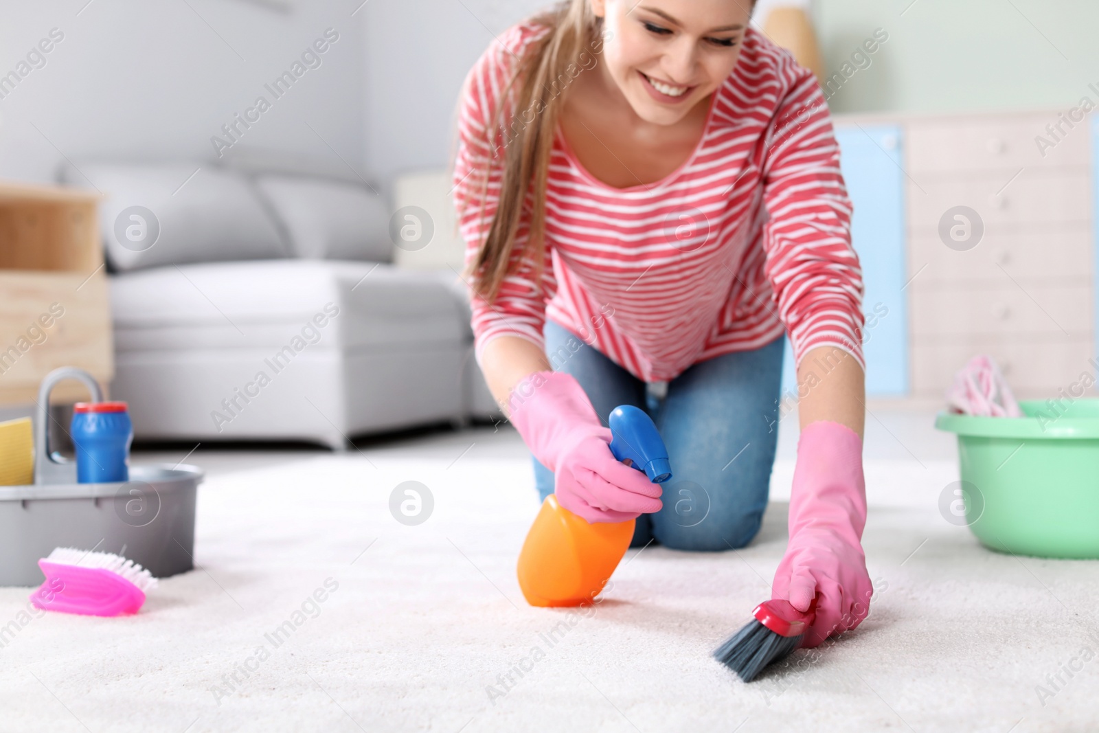 Photo of Young woman cleaning carpet at home