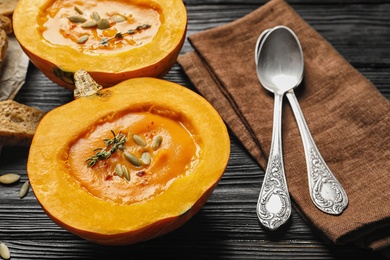 Tasty cream soup served in pumpkin on wooden table