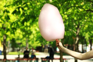 Woman holding sweet cotton candy in park, closeup