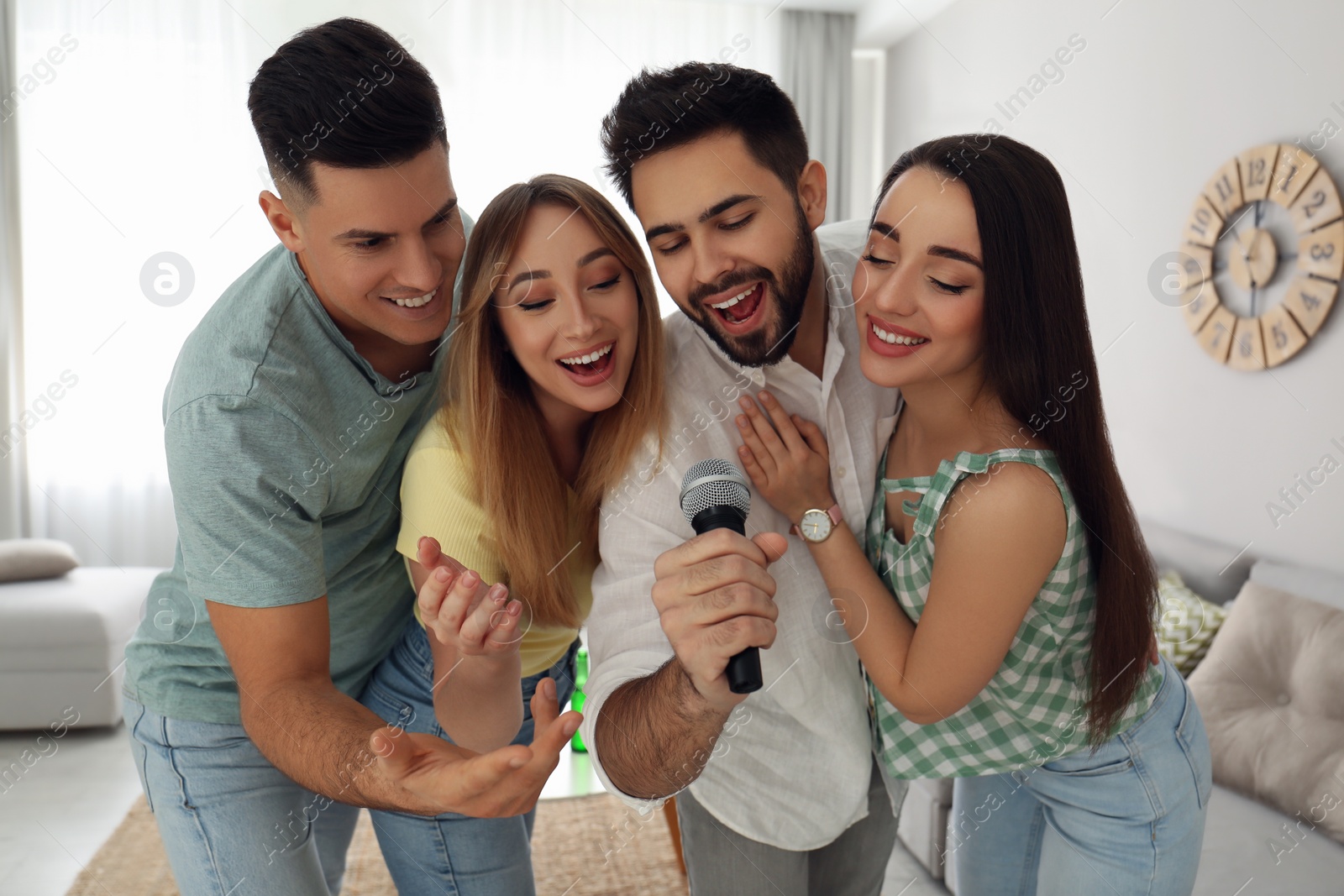 Photo of Happy friends singing karaoke together at home