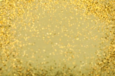 Photo of Blurred view of golden glitter on pale green background. Bokeh effect
