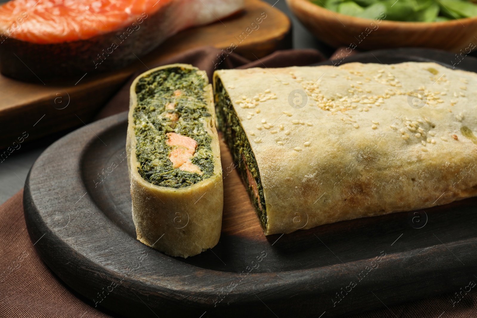 Photo of Delicious strudel with salmon and spinach on table, closeup