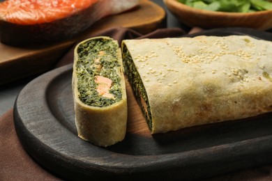 Delicious strudel with salmon and spinach on table, closeup