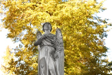 Photo of Beautiful statue of angel at cemetery, low angle view. Space for text