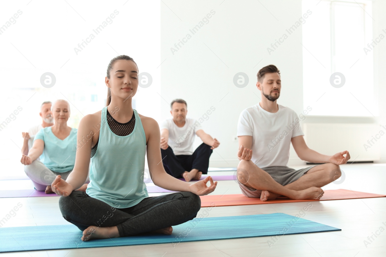 Photo of Group of people in sportswear practicing yoga indoors