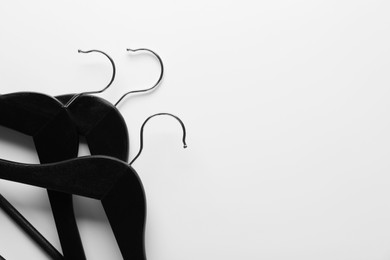 Photo of Black hangers on white background, top view. Space for text