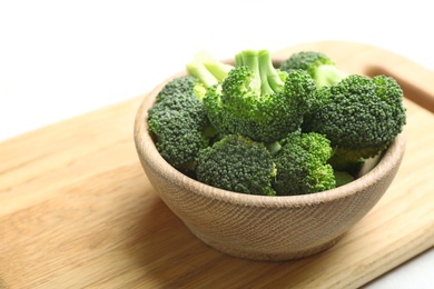 Bowl of fresh broccoli on wooden board, closeup