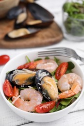 Photo of Bowl of delicious salad with seafood on white wooden table, closeup