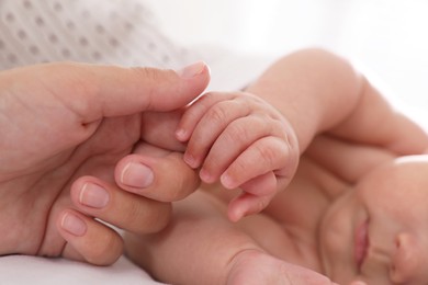 Photo of Mother with her cute baby on bed, closeup of hands