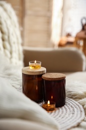Photo of Candles on beige sofa with knitted blanket. Interior decor