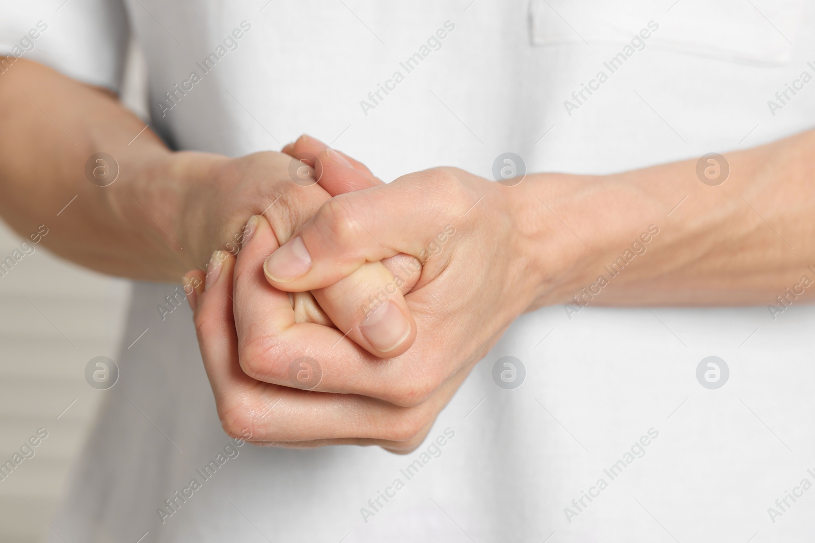 Photo of Woman cracking her knuckles on blurred background, closeup. Bad habit