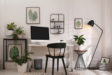 Photo of Comfortable workplace with modern computer and houseplants in room. Interior design