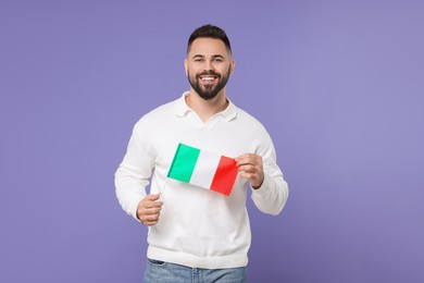 Young man holding flag of Italy on purple background