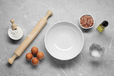 Bowl and different products on grey table, flat lay